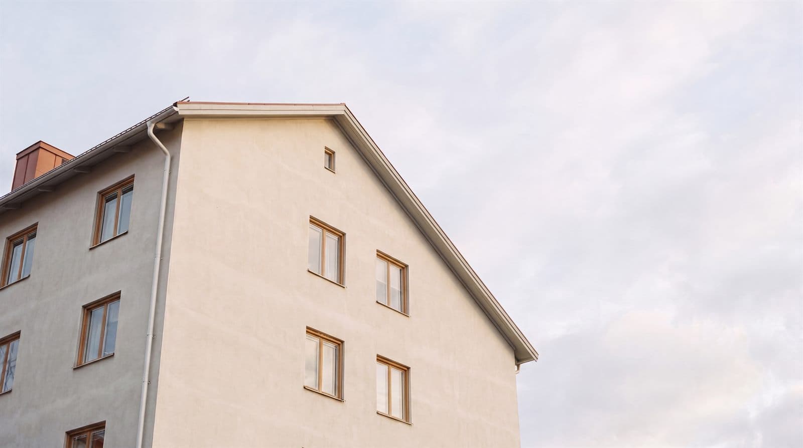 Putsad fasad på flerbostadshus mot ljus himmel